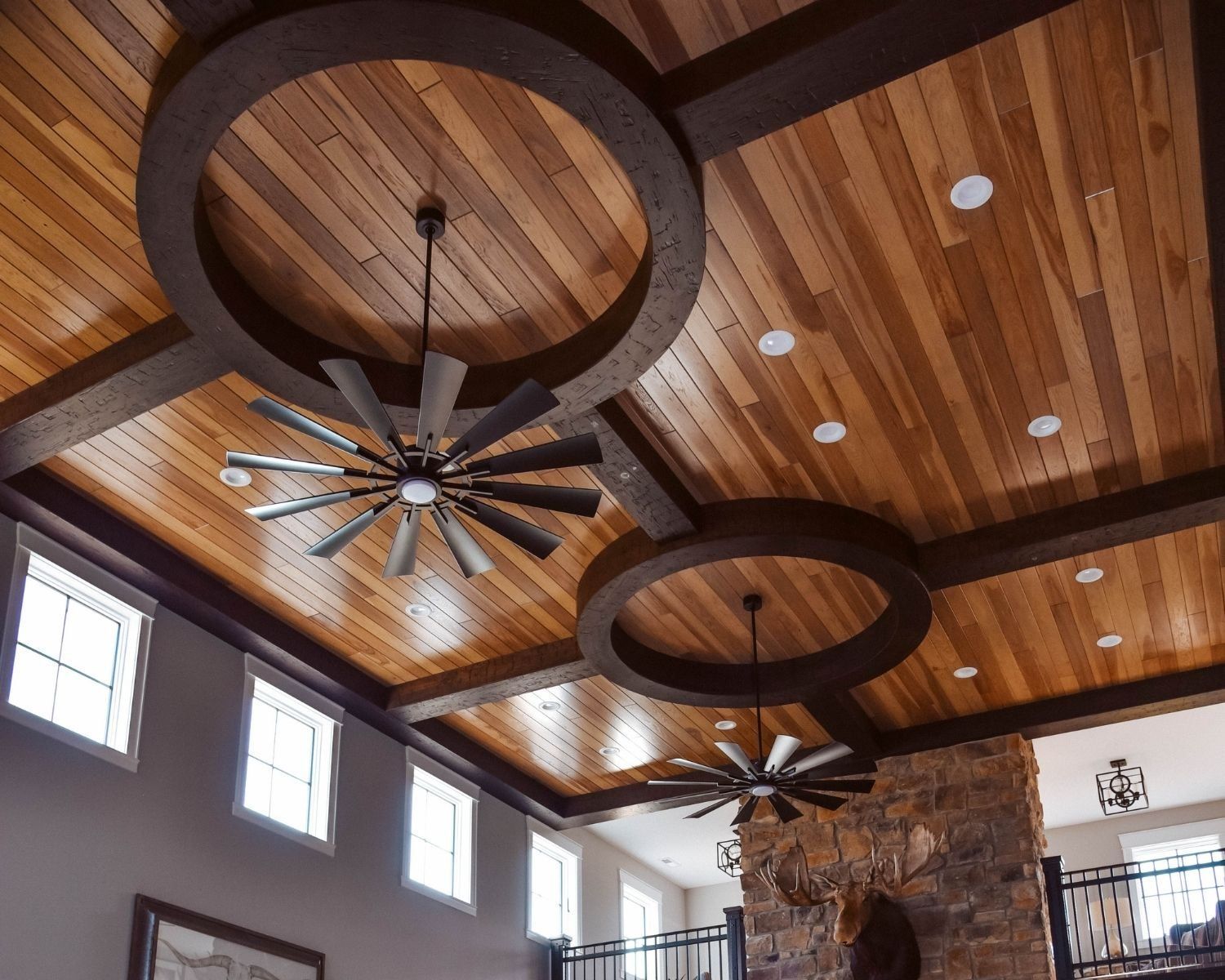 A living room with a wooden ceiling and ceiling fans