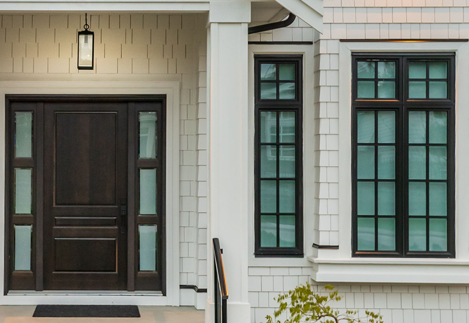 A white house with a brown door and black windows.