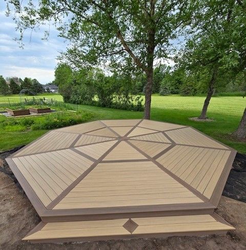 A wooden deck is sitting in the middle of a lush green field.