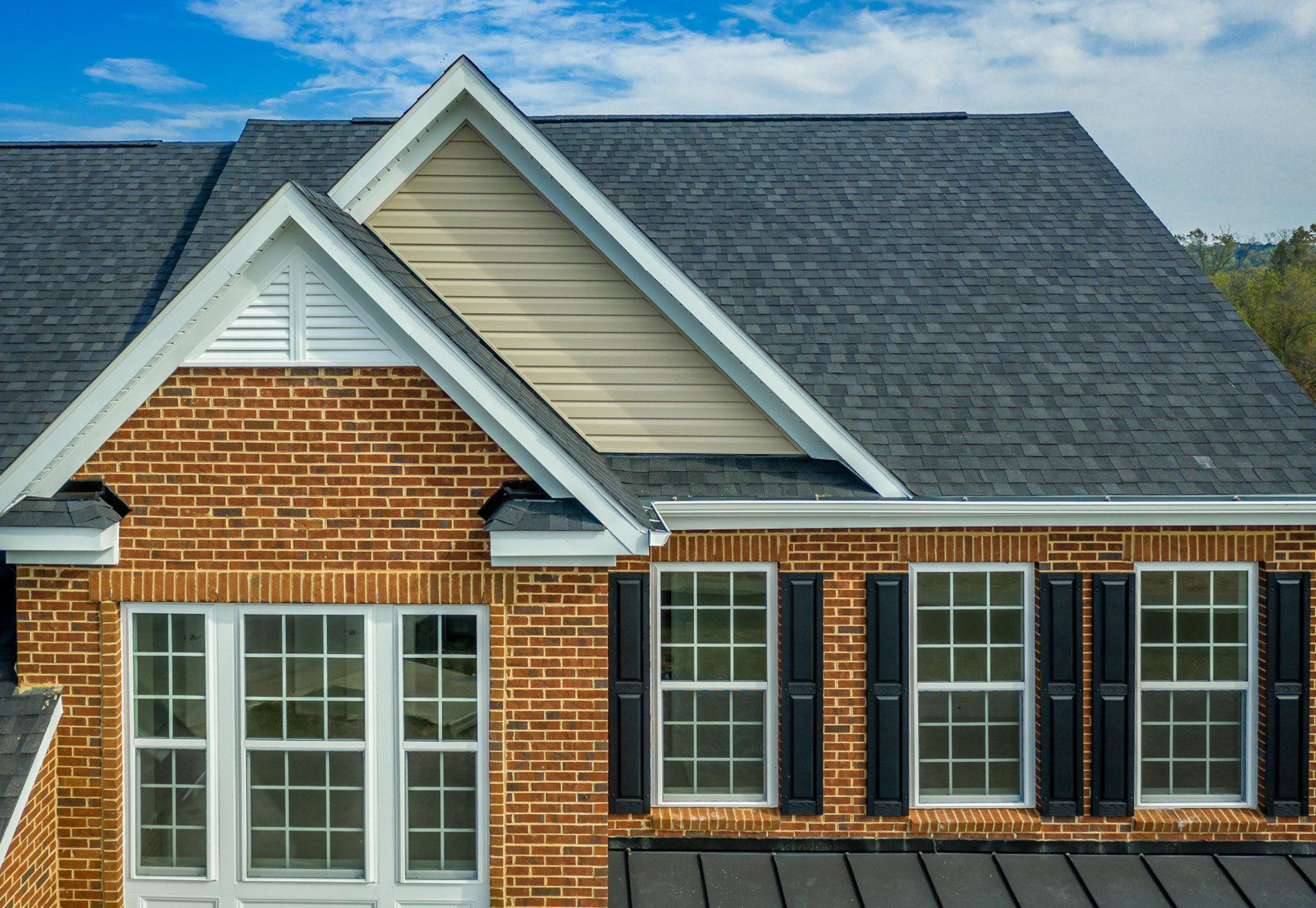 An aerial view of a brick house with a black roof and black shutters.