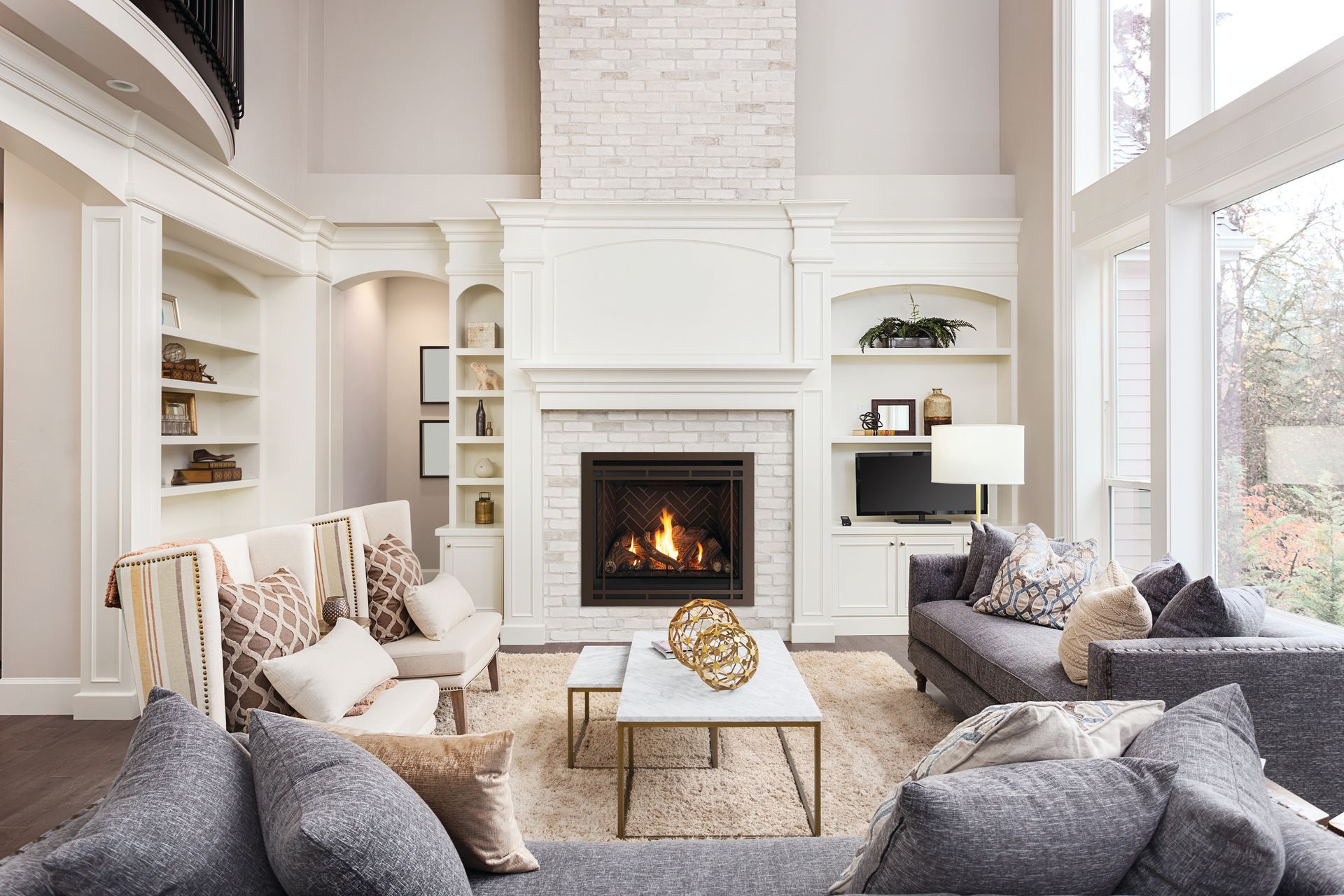 Bright living room with white fireplace, gray sofas, and large windows