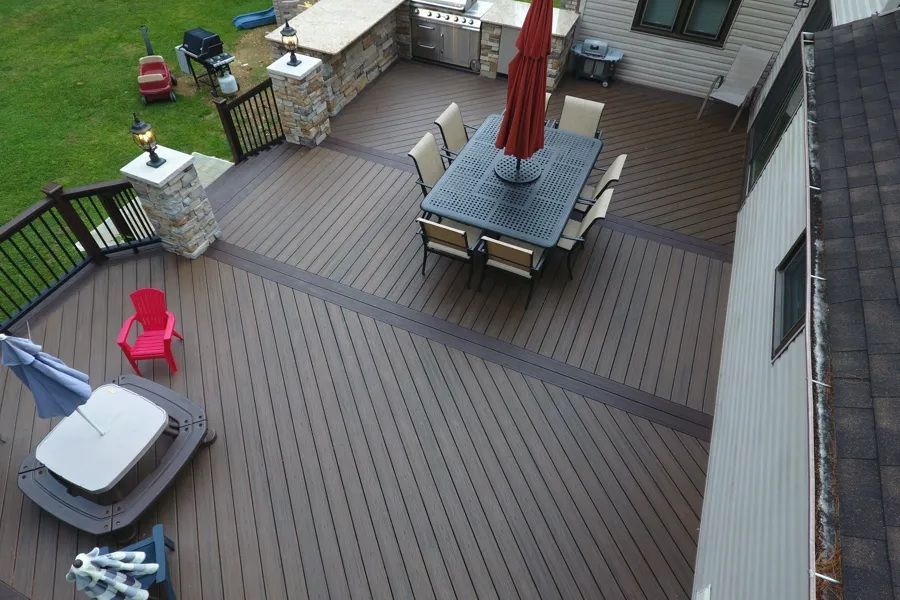 Overhead view of a wooden deck with patio furniture, red umbrella, grill, and a small grassy yard