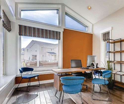 A room with a desk and chairs and large windows