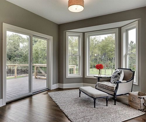 A living room with a chair , bench, sliding glass doors and windows leading to a deck.