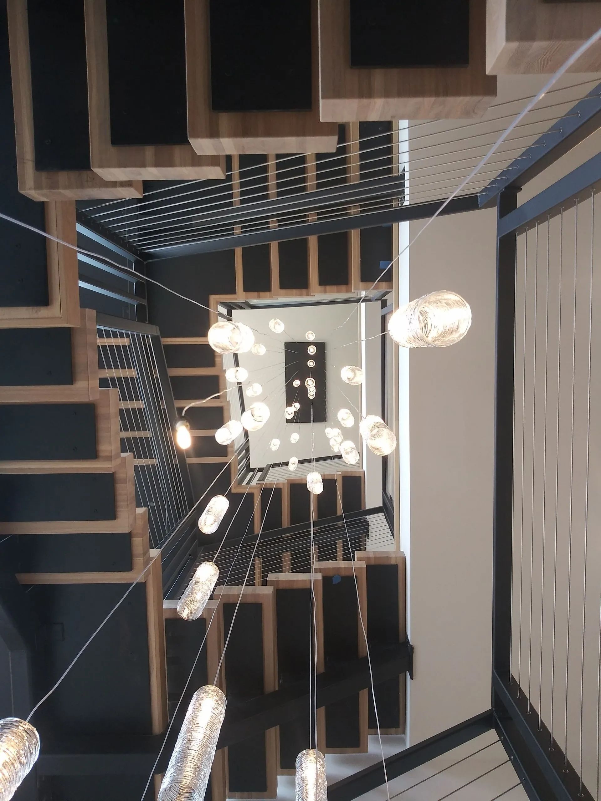 Modern staircase with hanging pendant lights and black-and-white geometric wall decor