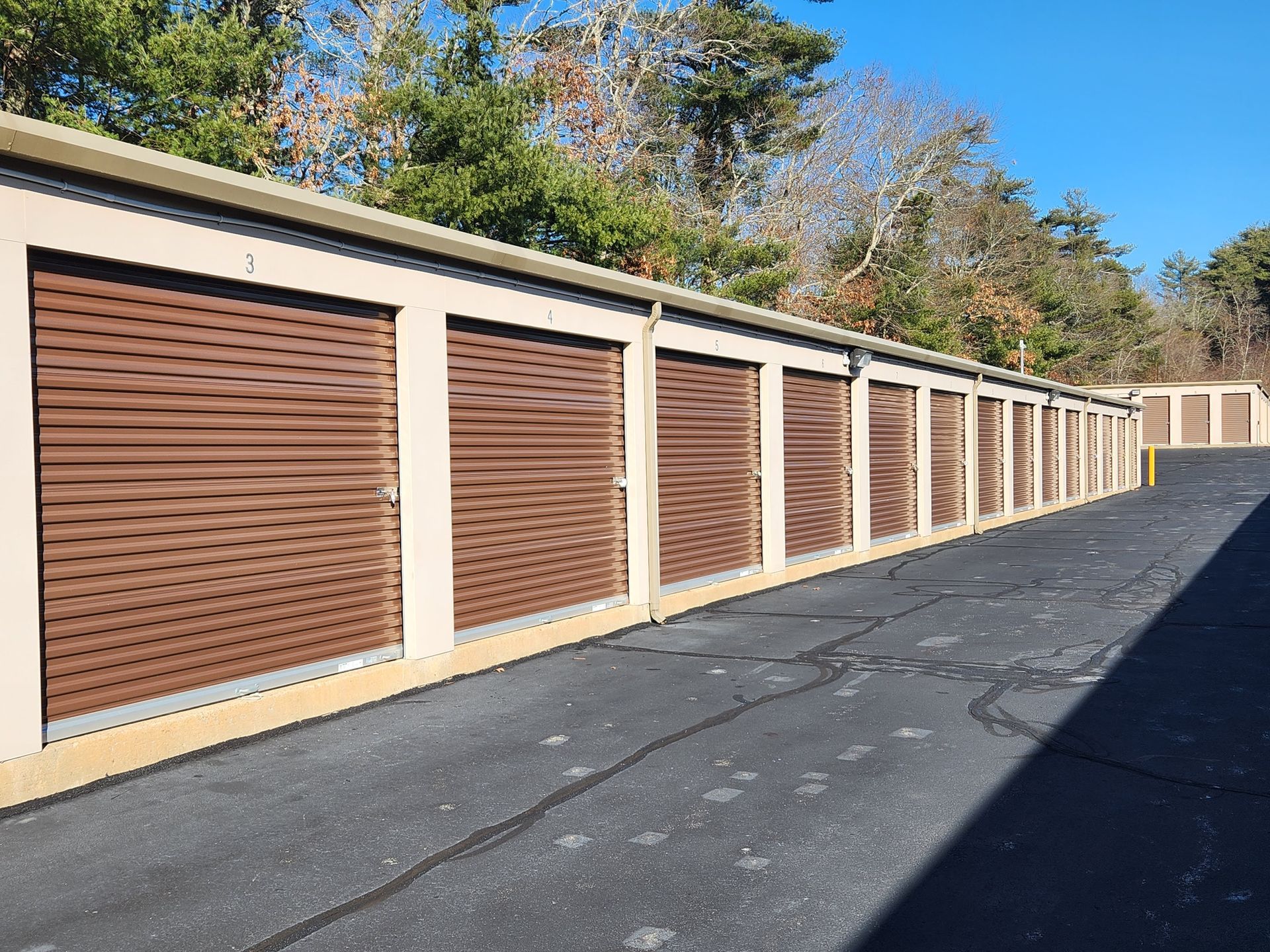 a row of storage units with brown doors on a sunny day