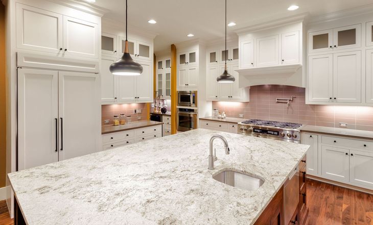 Bright modern kitchen with white cabinets, granite island, pendant lights, and hardwood floors.