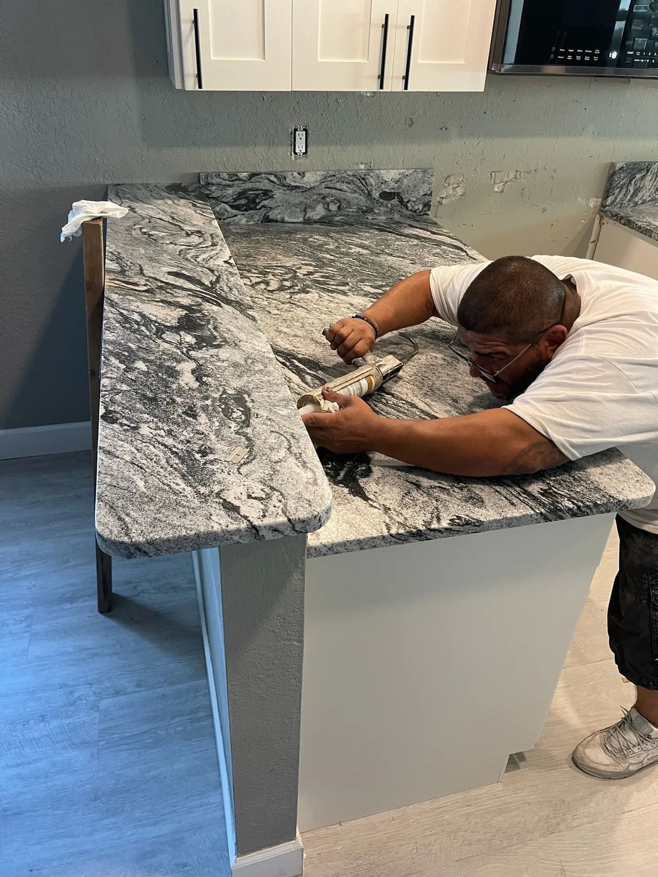 Worker smoothing granite countertop in a kitchen renovation