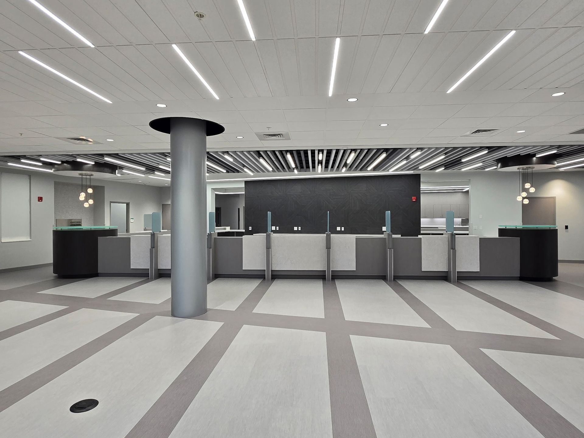 Empty modern airport check-in area with counters, gray flooring, and overhead strip lights