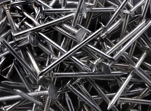 Pile of shiny metal nails scattered in a heap on a dark background