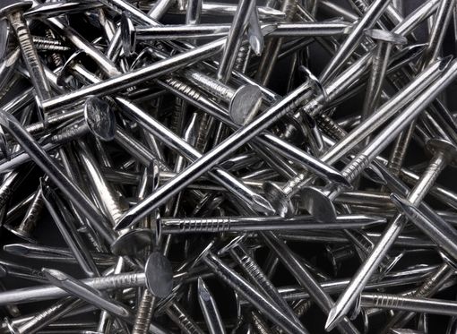 Pile of shiny metal nails scattered in a heap on a dark background