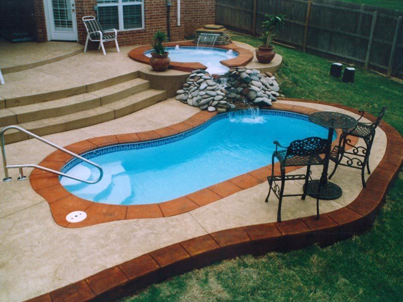 Backyard with a small, unique pool, hot tub, waterfall, and patio furniture.