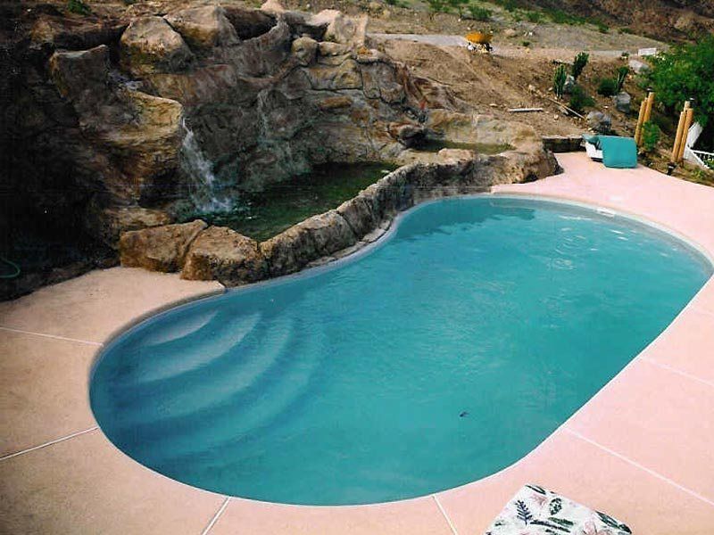 Swimming pool with a waterfall feature surrounded by rock formations.