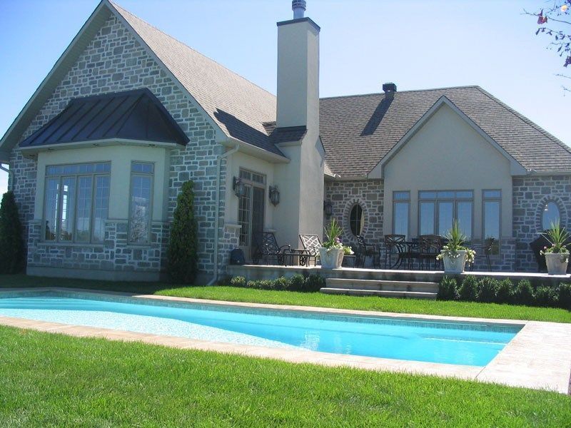 House with stone exterior and pool in backyard.