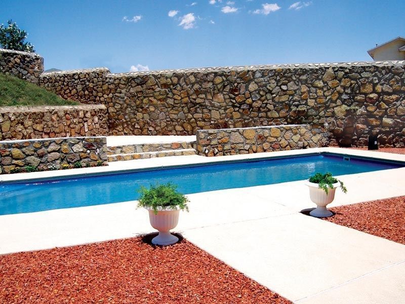 Swimming pool bordered by stone walls, sunny day.