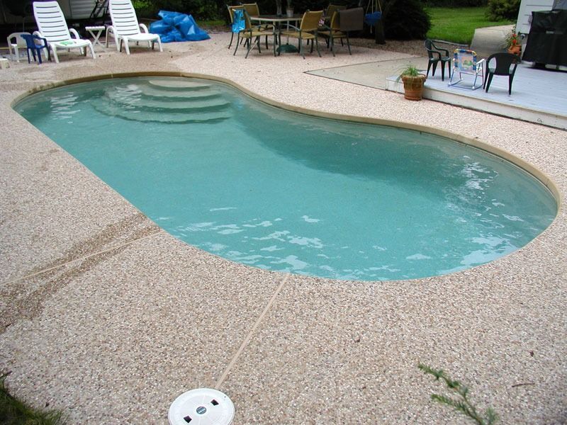 A kidney-shaped swimming pool with a concrete patio.