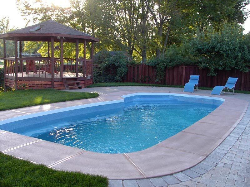 Swimming pool in backyard with gazebo, lounge chairs, and brick patio.