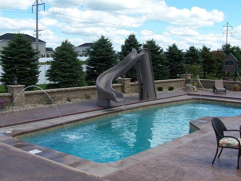 Pool with water slide, fountains, and patio.