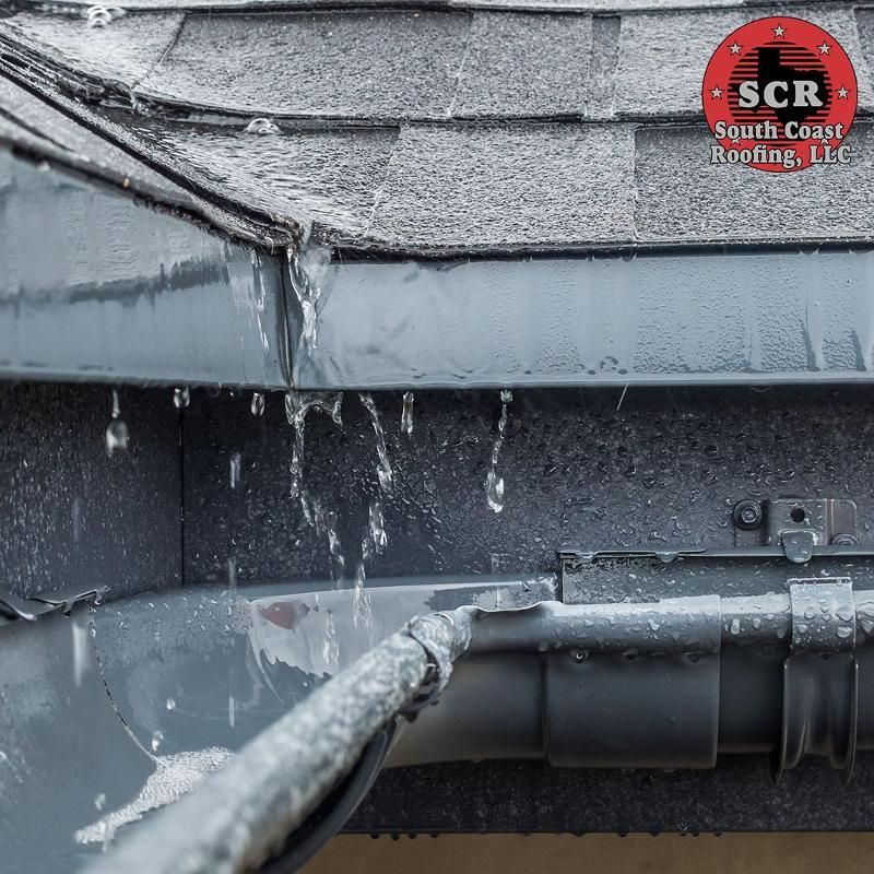 A gutter on a roof with water coming out of it