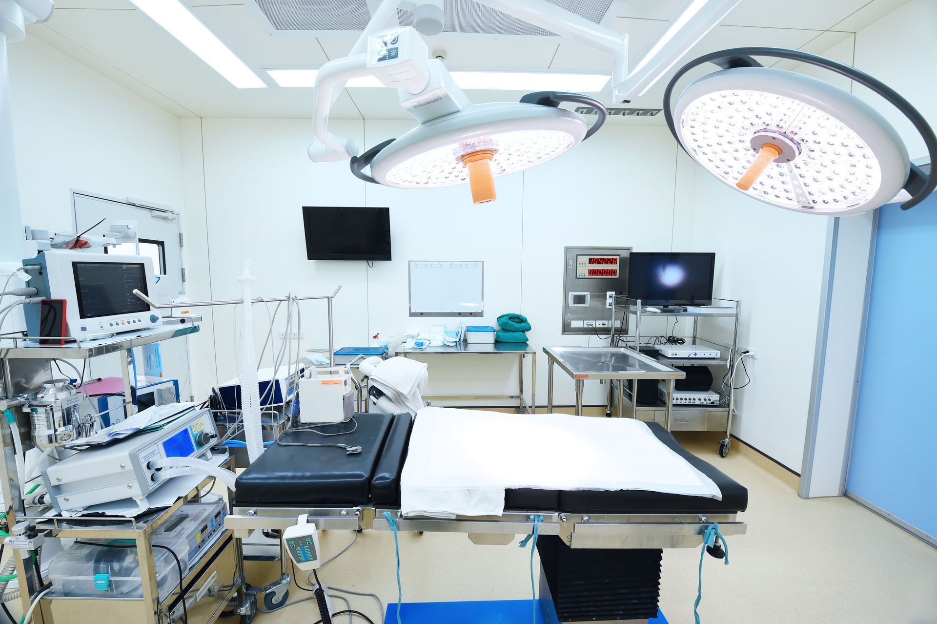 Surgical room with operating table, medical equipment, and overhead lights.