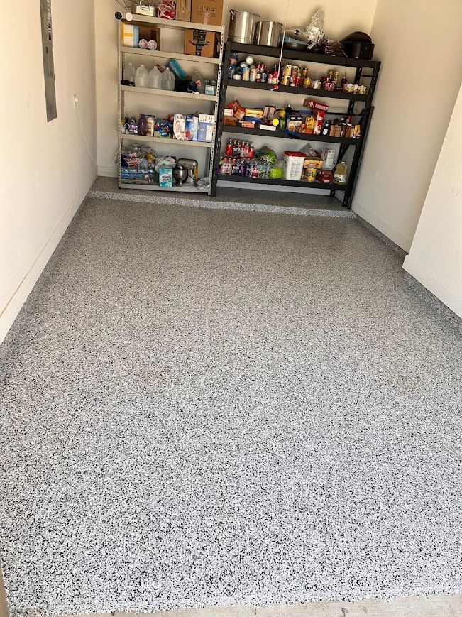 Garage with gray speckled epoxy floor and storage shelves filled with items.