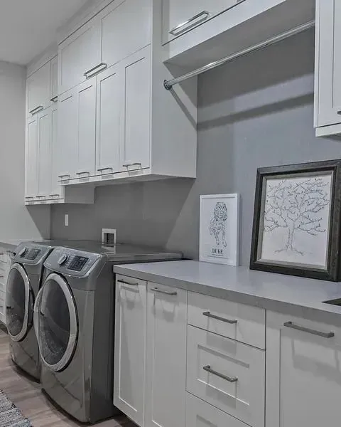 Laundry room with white cabinets, gray countertops, washer and dryer, and framed wall art