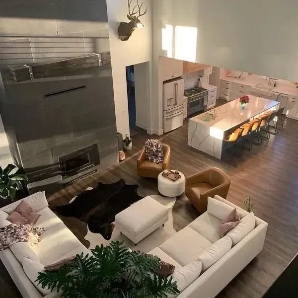 Spacious modern living room with white sofas, fireplace, dining table, and hardwood floors