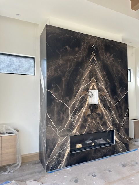 Black marble fireplace wall with TV mount, built-in shelf, and light wood flooring in a modern room