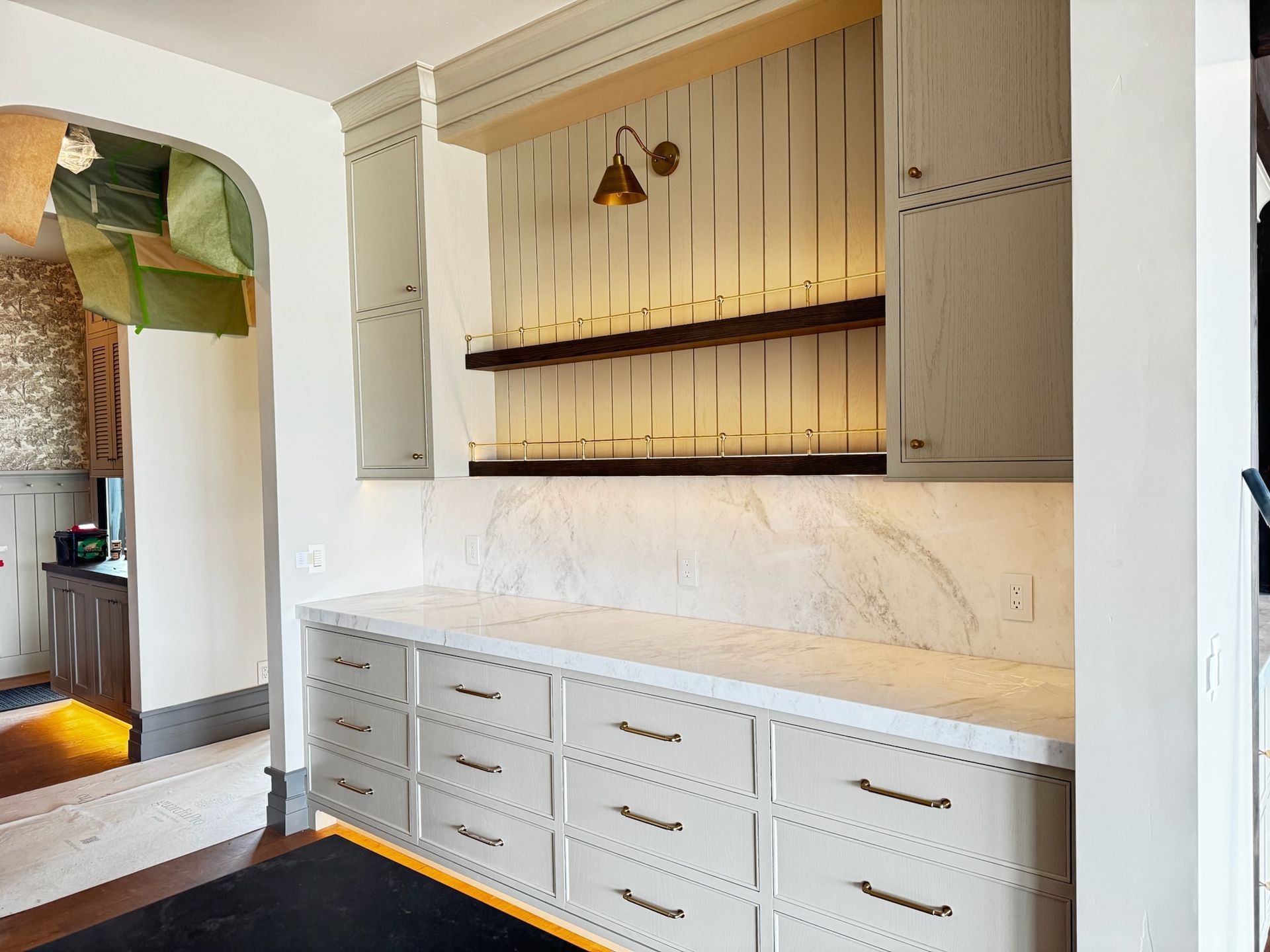 Bright kitchen with white cabinets, marble backsplash, open wood shelves, and pendant lights.