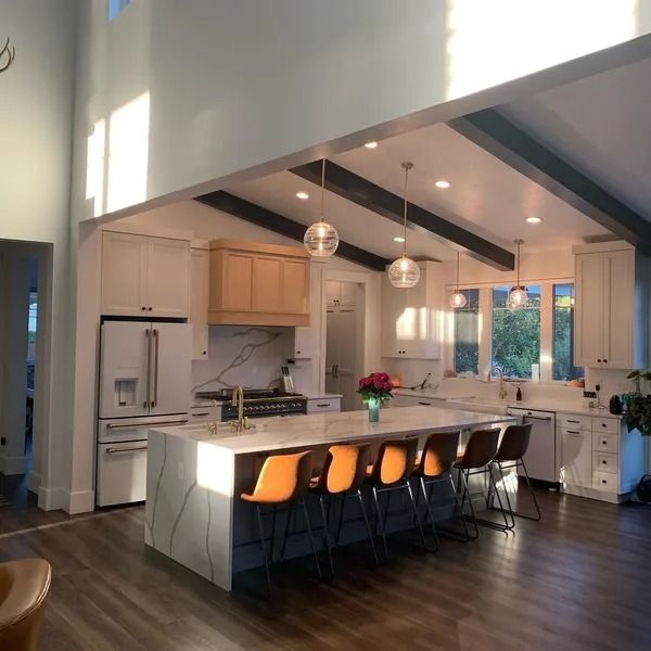 Modern kitchen with a large island, stainless steel appliances, and high ceilings.