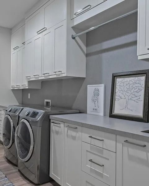 Laundry room with white cabinets, gray countertops, and front-load washer and dryer.