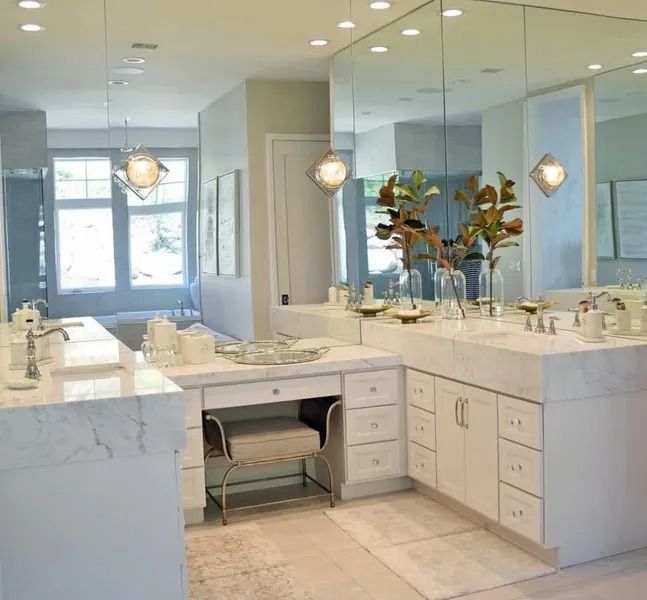 Modern white bathroom with marble countertops and large mirrors.
