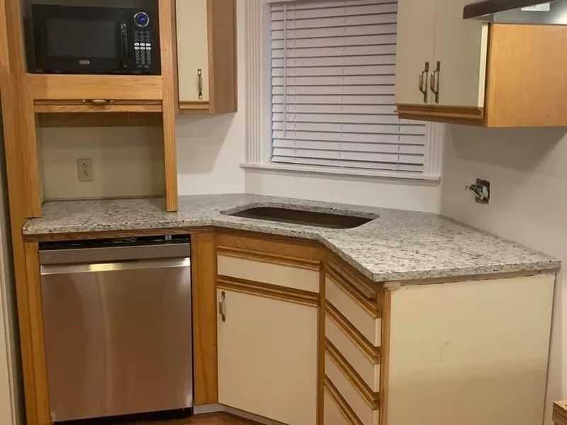 Small kitchen with granite countertop, stainless steel dishwasher, microwave, and cabinets.