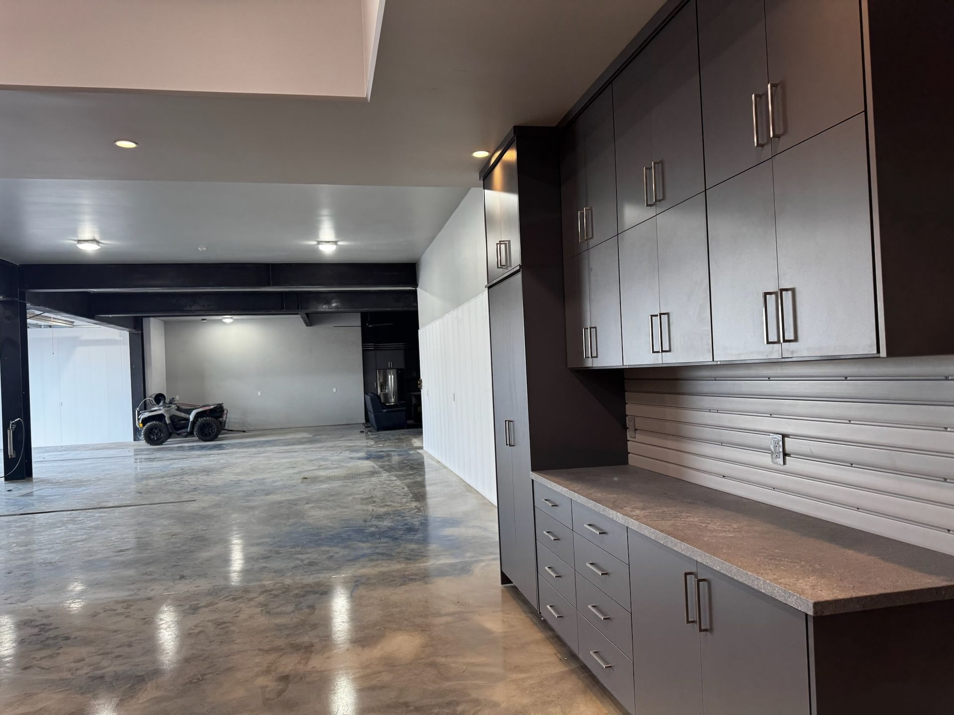 Spacious empty garage with polished concrete floor and built-in dark cabinets along the right wall