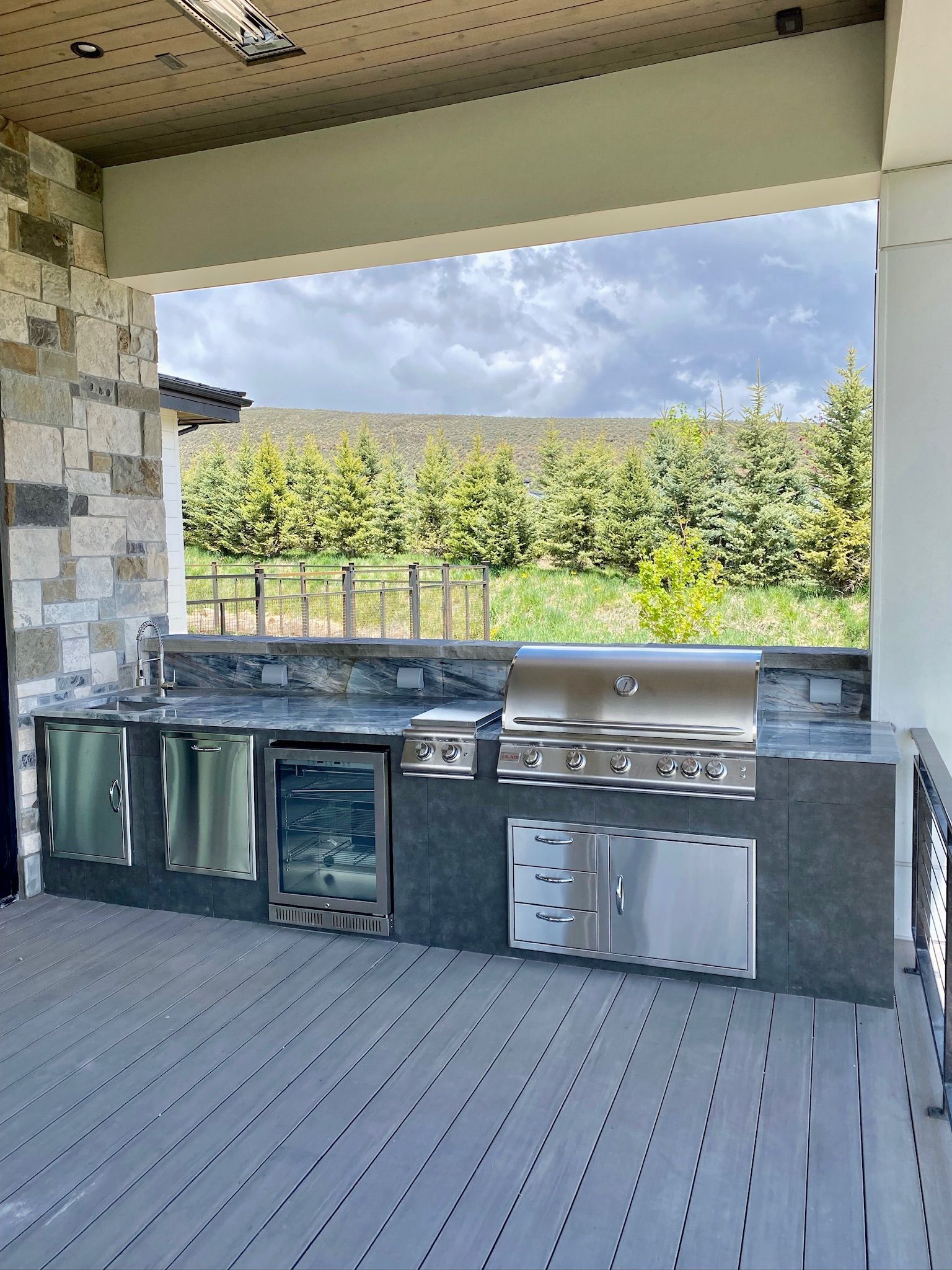Outdoor patio kitchen with grill, cabinets, and mini fridge under a covered area