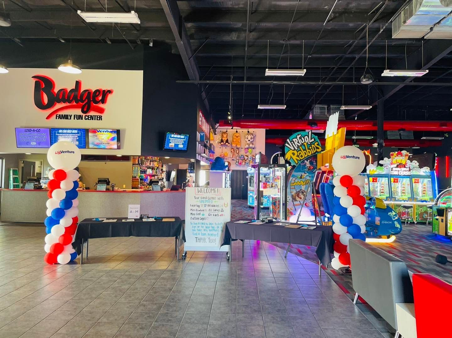 Arcade entrance with red, white, and blue balloon columns and colorful game machines inside