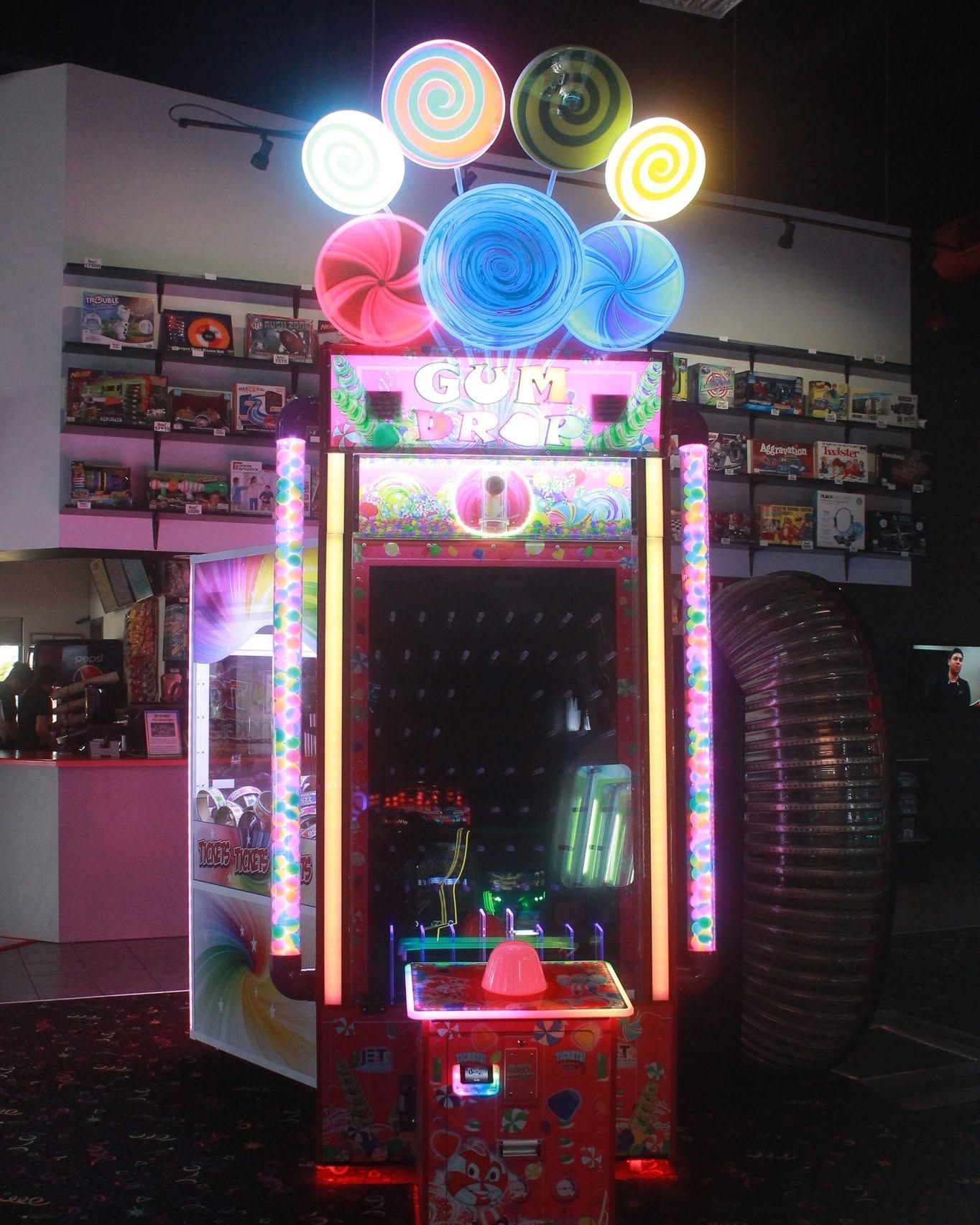 Colorful arcade game machine with bright neon lights and spiral lights on top in a dark game room
