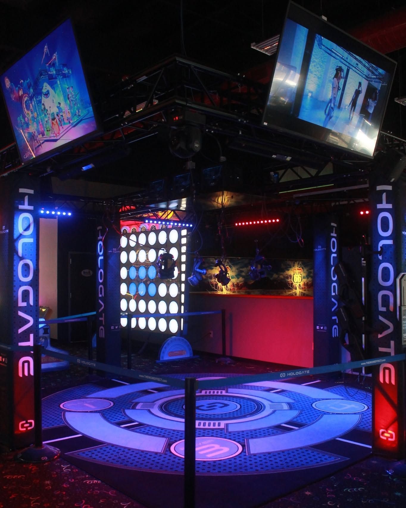 Neon-lit arcade booth with screens, colorful lights, and a glowing circular dance floor