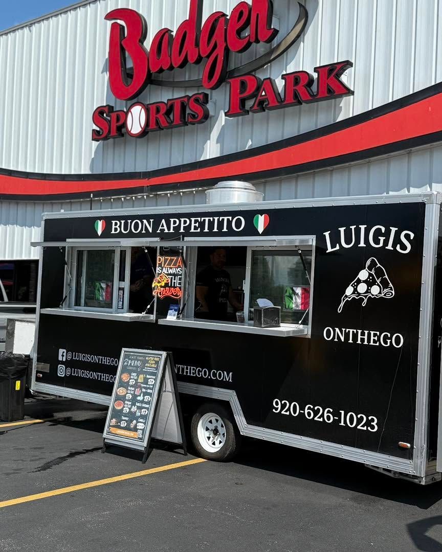 Food truck at Badger Sports Park, black with red and white signage reading “Luigi’s On the Go.”