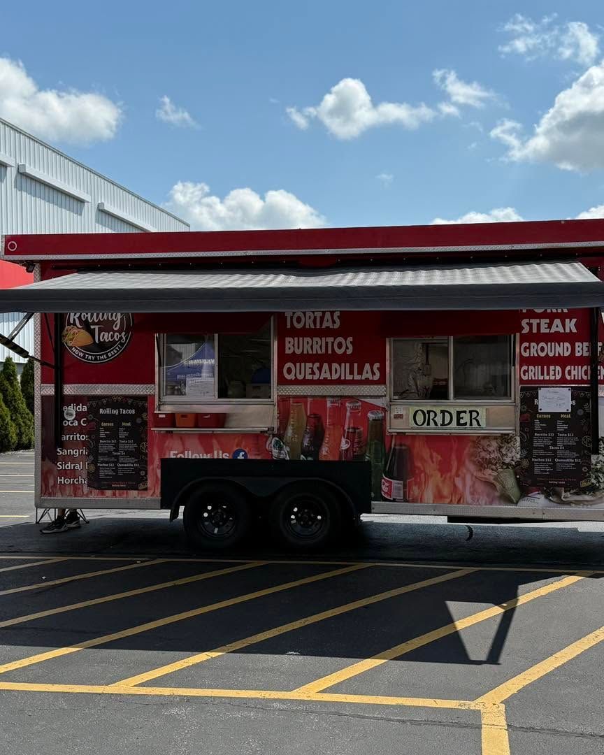 Red food truck with menu signs parked in a lot under a blue sky