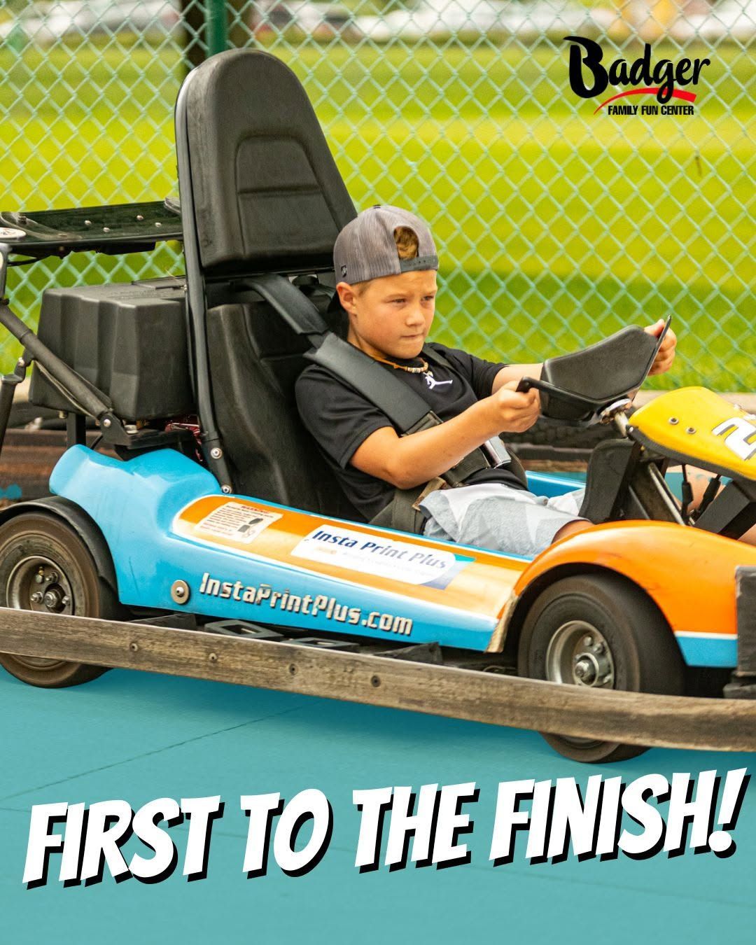 Child driving a blue-and-orange go-kart on a track, with “First to the Finish!” text