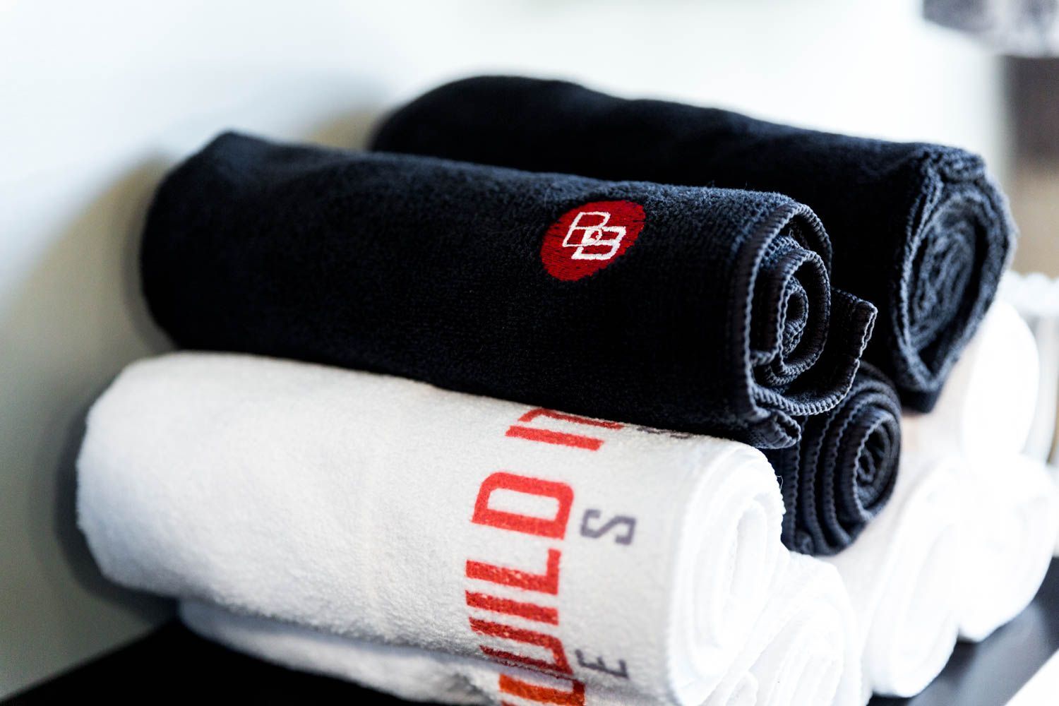 Rolled towels: black with a red logo and white with red text stacked on top of each other.