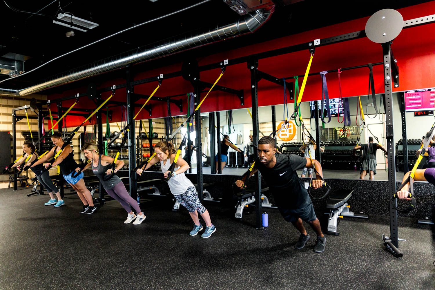 People exercising with suspension trainers in a gym.