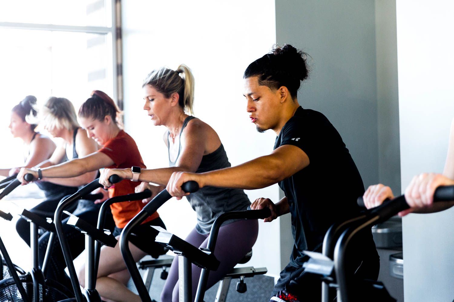 People working out on stationary bikes in a gym setting.