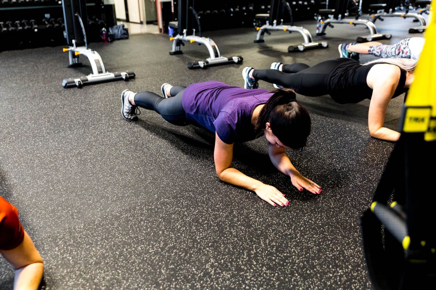 People doing planks on a gym floor. Women in workout clothes.