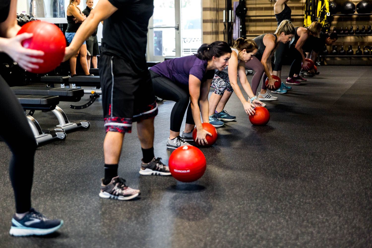 People in gym doing exercise with red medicine balls.