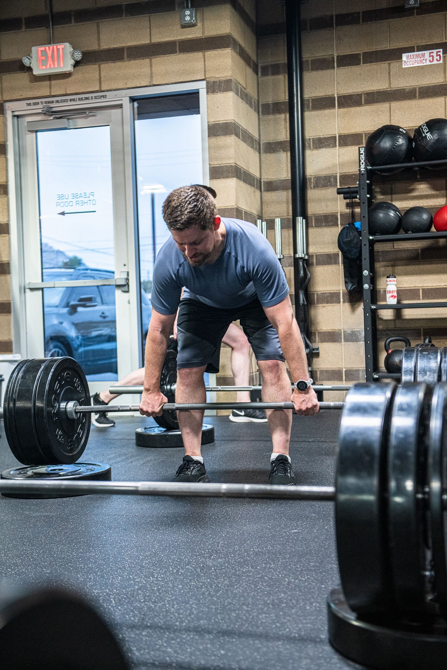 Man lifting barbell in a gym, preparing for deadlift.