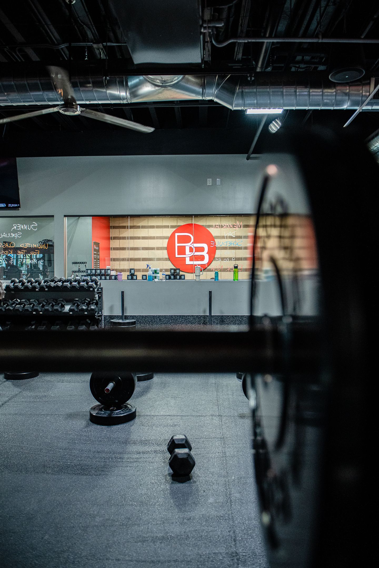 Barbell in foreground, gym interior. 