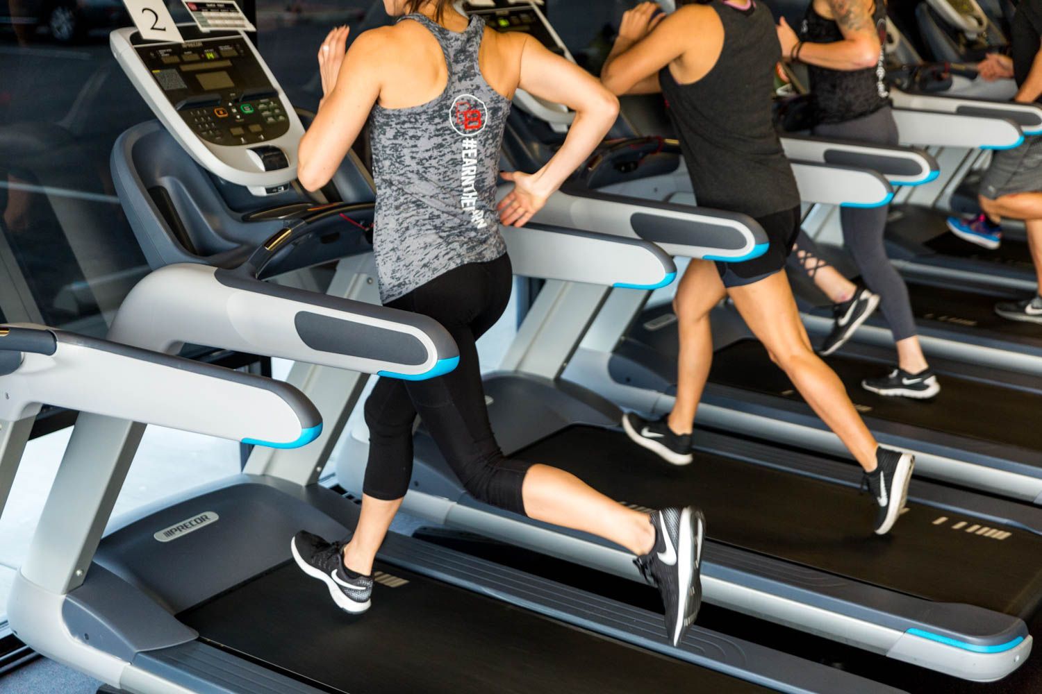 People running on treadmills in a gym setting, focused on fitness training.