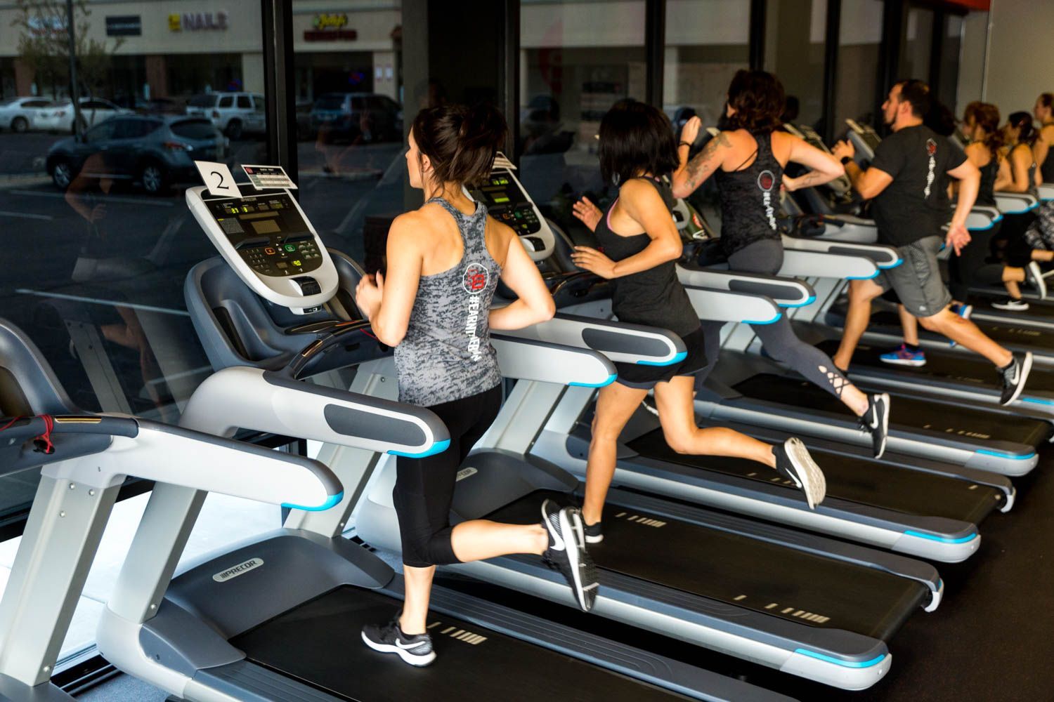 People running on treadmills in a brightly lit gym.